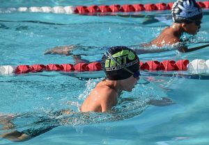 Image is of two boys swimming competitively in a pool.
