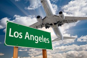 Image is a plane landing over a Los Angeles sign.