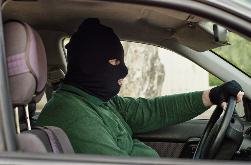 Bank robber in black balaclava waiting inside a car