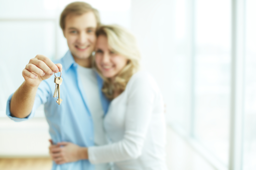 Image of young happy couple embracing while man showing key from new flat