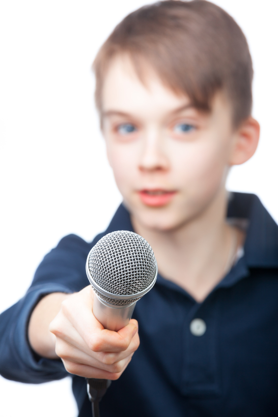 Boy holding a microphone conducting an interview, focus on microphone face is blurred