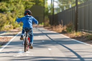 Image is of a boy riding his bike on a bike lane.