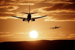 Image is of two air jet planes taking off and landing with the setting sun behind them