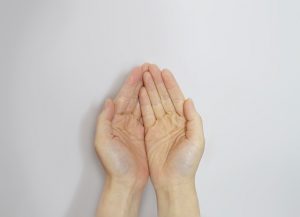 Image is of two hands, forming a bowl, held out asking for a donation