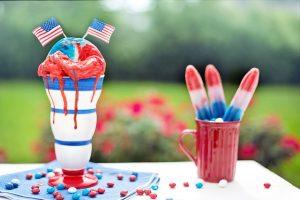 Image is red, white, and blue desserts and popsicles against an outdoor background.
