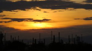 Image is an oil refinery silhouette at sunset.