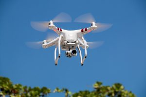 Image is of a white drone against a blue sky.