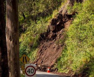 Image is of a small landslide along a paved road.