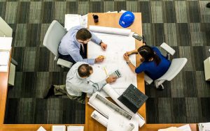 Image is an aerial view of a group of architects at a meeting.