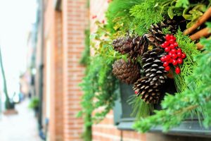Image is a close up of Christmas boughs and berries against a red brick wall.