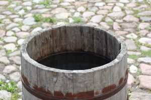 Image is a rain barrel on stone courtyard.