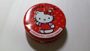 Image is a red tin of Hello Kitty strawberry cream candies.