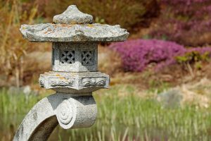 Image is a stone Japanese lantern in a garden.