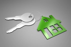 Image is a green keychain in the same of a house with two silver keys attached.