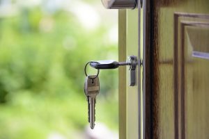 Image is a picture of house keys hanging in an outside door lock.