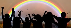 Image is a rainbow with children in front of it, cast in shadow.