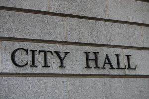 Image is a city hall sign on a brick building.