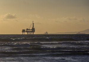 Image is an offshore drilling rig and tankers.