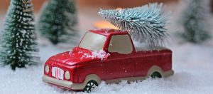 Image is a toy truck pretending to carry a miniature Christmas Tree in its bed.