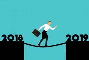 Image is of a business woman walking a rope between 2018 and 2019.