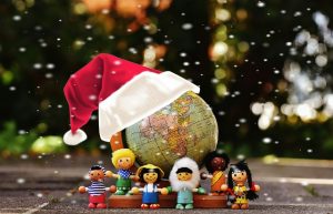Image is a small globe topped by a Christmas hat with dolls of different nationalities gathered around it.