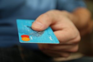 Image is a man holding out a credit card for payment.