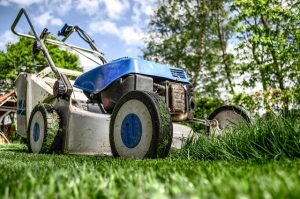 Image is a close up of a lawn mower in the spring cutting grass.