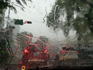 Image is heavy summer rains as seen through the windshield of a car.