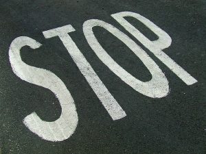 Image is a close up of the word Stop painted on asphalt.