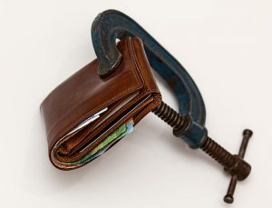 Image is a wallet being squeezed by a vice.