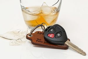 Image is a broken glass of alcohol next to a set of car keys.