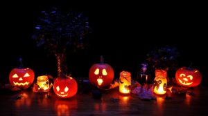 Image is a line of jack o lanterns and candles glowing for Halloween.