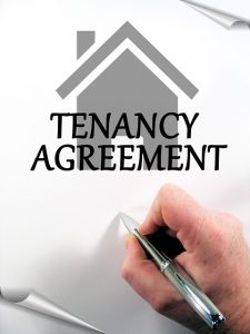 Image is a hand signing a tenancy agreement.