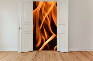 Image is two open doors in a home with fire behind them.