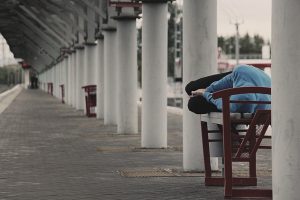 Image is a man sleeping on a table in an outdoor area.