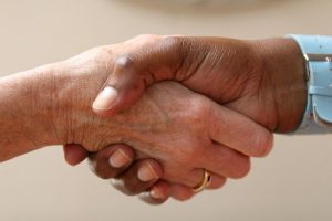 Image is a close up of two women shaking hands.