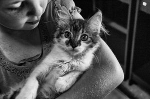 Image is a black and white photo of a girl with a cat in her arms.