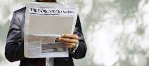 Image is a man holding a newspaper that says "the world is changing" on the front.
