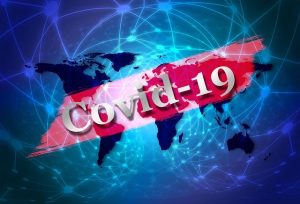 Image is the word Covid-19 superimposed over a world map.