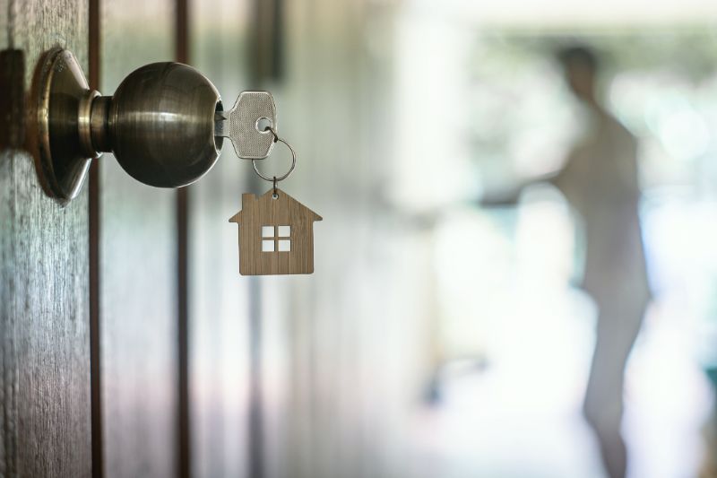 house key with home keyring in keyhole on wood door