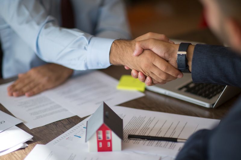 estate agent shaking hands with his customer after contract signature