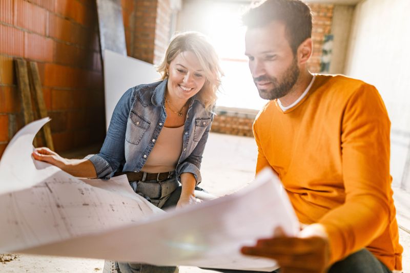 happy couple analyzing plans at their renovating apartment