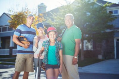portrait of smiling multi generation family with baseball bat in street